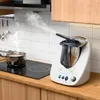 A kitchen scene with a cooking appliance and a pot on a stove. Produktbild-Vorschau