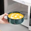 A hand places a bowl of soup into a microwave. Náhled obrázku produktu