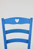 The back of a blue wooden chair with a heart cutout in the top. Produktbild-Vorschau