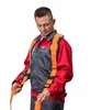 A man wearing a red and gray work uniform and an orange safety harness is adjusting the straps. Produktbild-Vorschau
