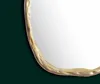 A close-up of the edge of an oval mirror with a textured gold frame, set against a dark green background. Podgląd zdjęcia produktu