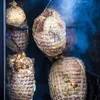 Several pieces of meat wrapped in netting are hanging in a smoker, with visible smoke. Produktbild-Vorschau