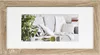 A framed picture of a modern living room sofa with decorative pillows and plants. Produktbild-Vorschau