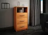 A wooden chest of drawers with three drawers and an open shelf, placed in a room with a wall, curtains, and a sofa. Produktbild-Vorschau