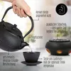 A hand pouring tea from a cast iron teapot into a cup, with a tea warmer in the background. Produktbild-Vorschau
