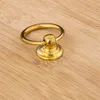 A close-up shot of a golden ring pull handle on a wooden surface. Produktbild-Vorschau