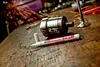 A paint marker and metal components are on a wooden workbench with sparks flying in the background. Produktbild-Vorschau