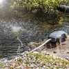 A pond aeration pump is placed on rocks next to a pond, with bubbles rising from the water. Produktbild-Vorschau