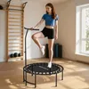 A woman is exercising on a mini trampoline in a room with exercise equipment. Produktbild-Vorschau