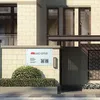 A sign with company information and QR codes is mounted on a stone wall in front of a building entrance. Náhľad obrázku produktu