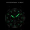A close-up of a luminous watch face in the dark, with text overlay. Produktbild-Vorschau