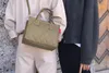 Two people standing next to each other, one holding a small quilted bag. Voir les images du produit
