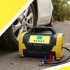 A portable air compressor is shown next to a car tire on the ground. Produktbild-Vorschau