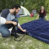 A couple setting up camp, inflating an air mattress near a tent. Náhled obrázku produktu