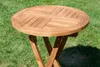 A round wooden folding table is shown outdoors on a grassy lawn. Produktbild-Vorschau