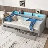 A gray upholstered daybed with storage drawers, set up in a bedroom with decorative pillows and blankets. Produktbild-Vorschau