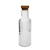 A clear glass bottle with vertical ridges and a cork stopper, isolated on a white background. Náhľad obrázku produktu
