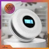 A white carbon monoxide and smoke detector is displayed on a white pedestal against a blurred indoor background. Podgląd zdjęcia produktu