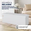 A white storage bench is shown in a living room setting with a sofa and a side table in the background. Produktbild-Vorschau