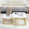Two nesting coffee tables with marble-effect tops and gold metal frames are shown in a living room setting, with a sofa and blanket in the background. Náhľad obrázku produktu