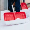 A person is shoveling snow with a red snow shovel. Náhled obrázku produktu