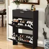 A black shoe cabinet with multiple shelves and drawers, filled with shoes, is shown in a hallway next to a dining area. Náhľad obrázku produktu