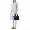 A woman is standing and holding a black crossbody bag. Produktbild-Vorschau