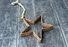 A rusty star ornament hangs from a twine string on a weathered wooden surface. Produktbild-Vorschau