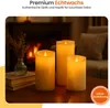 Three LED candles are arranged on a wooden table in front of a fireplace, with a vase of dried flowers to the left. Produktbild-Vorschau