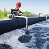 A worker in safety gear inspects equipment at a water treatment facility. Produktbild-Vorschau
