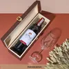 A wine bottle in a wooden box next to a wine glass and dried flowers. Produktbild-Vorschau