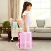 A young girl walks through a living room carrying a pink toy wardrobe. Produktbild-Vorschau