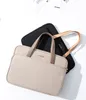Two laptop bags are shown, one beige and one black, on a white background. Papers are visible in the background. Produktbild-Vorschau