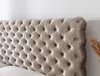 A close-up view of a tufted beige headboard. Produktbild-Vorschau