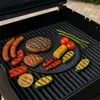 A variety of food items are arranged on a black grill grate, suggesting a barbecue. Produktbild-Vorschau