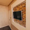 A modern living room with a TV mounted on a stone-tiled wall. Produktbild-Vorschau