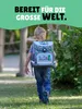 A young boy walks away from the camera, wearing a backpack. Produktbild-Vorschau