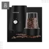 A black coffee grinder with a clear container filled with coffee beans, placed on a black surface with scattered coffee beans. Podgląd zdjęcia produktu