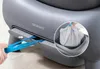 A close-up view of a person's hand pulling blue plastic bags from a gray automatic cat litter box. Anteprima dell’immagine prodotto