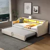 A beige daybed with a pull-out trundle bed is set up in a room with a window and artwork on the wall. Produktbild-Vorschau