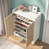A shoe cabinet with its doors open, displaying multiple shelves filled with shoes. The cabinet is placed in a room with a teal wall and a wooden floor. Produktbild-Vorschau