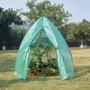 A green greenhouse with plants inside, set up in a grassy outdoor area with trees in the background. Produktbild-Vorschau