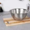 A stainless steel colander with a handle sits on a wooden cutting board, with a bottle of olive oil and a pepper grinder visible in the background. Náhľad obrázku produktu