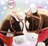 Two plush toy horses of different sizes, one labeled 105 cm and the other 125 cm, are shown side-by-side against a colorful, polka-dotted background. Both horses are equipped with brown harnesses and red bandanas around their necks. Podgląd zdjęcia produktu