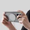 A person holding a smartphone horizontally, with a magnetic charger attached to the back. Produktbild-Vorschau
