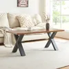A coffee table with a wooden top and black metal legs is placed on a rug in front of a sofa. A vase with dried flowers and a cup of coffee are on the table. Podgląd zdjęcia produktu