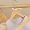 A hand is shown adjusting a pink shirt on a wooden hanger, with other hangers visible in the background. Náhled obrázku produktu