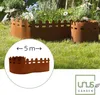 A rusty metal garden border with a picket fence design is shown in a garden setting. Produktbild-Vorschau