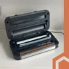 An open vacuum sealer machine is placed on a white countertop. Produktbild-Vorschau