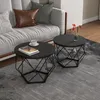 Two round coffee tables with geometric metal bases are placed on a rug in front of a sofa. One table has a book and a cup of coffee on it, while the other has a small vase with flowers. Produktbild-Vorschau